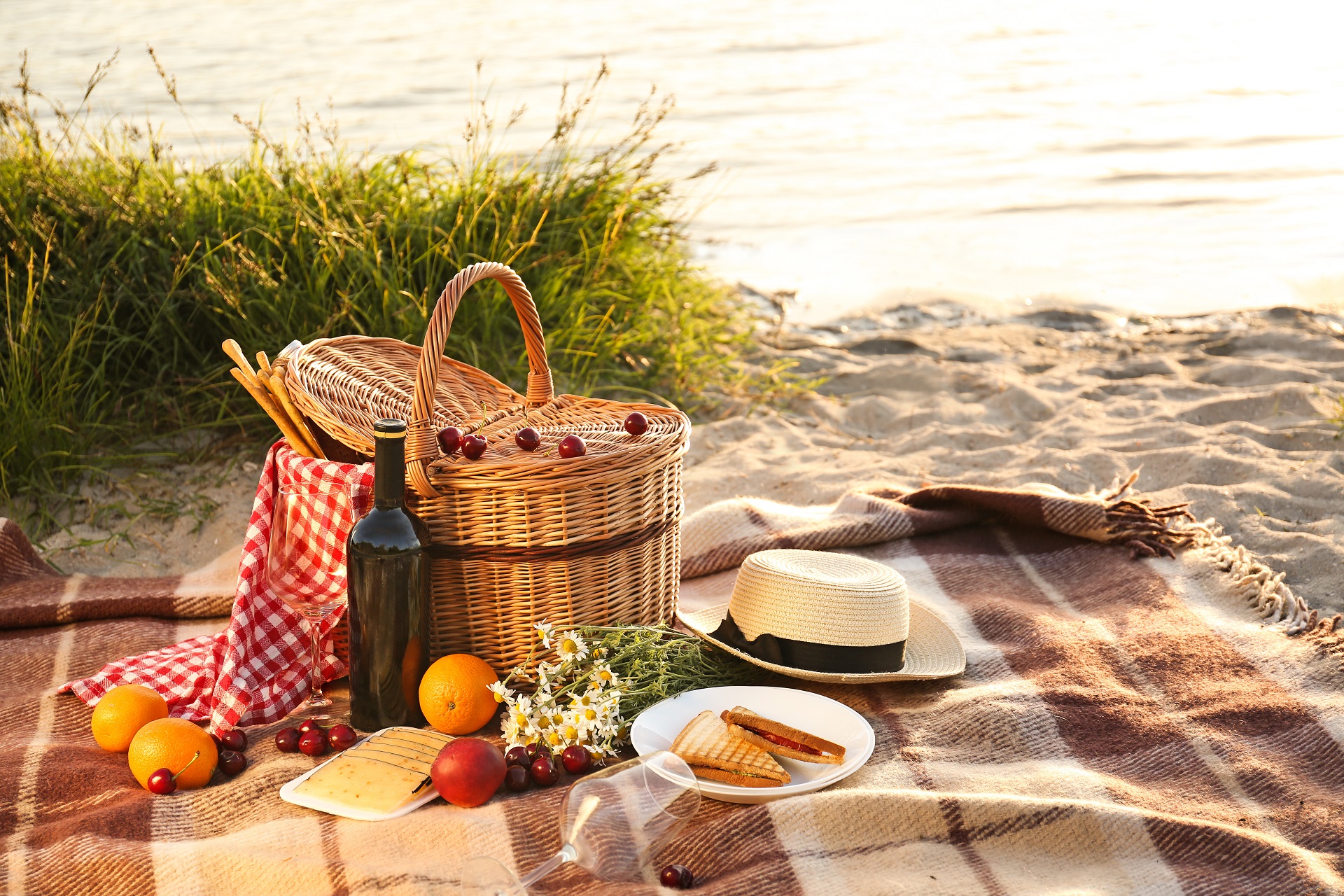 ALT: Korpa za piknik za romantičnu večeru na plaži u blizini rijeke.