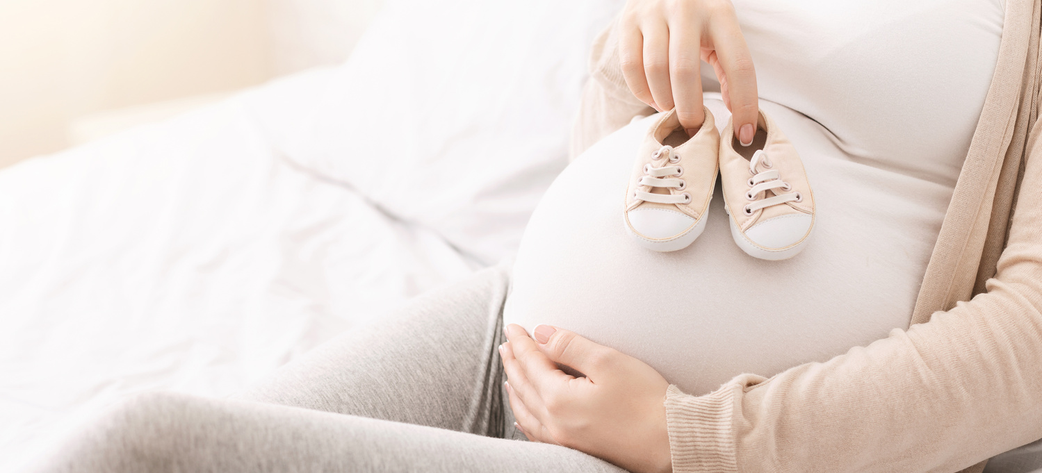 Trudnica drži na stomaku cipelice za bebe