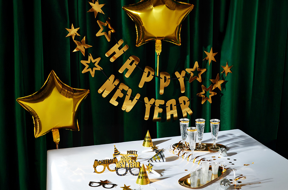 Sto dekorisan za Novu godinu, s balonima, čašama i zlatnim ukrasima.