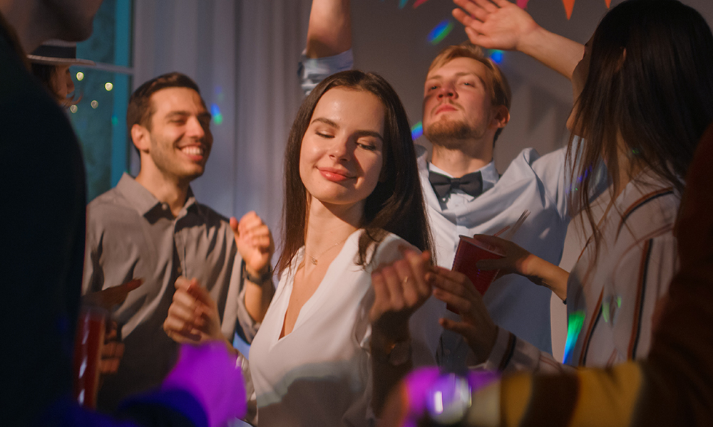 Grupa ljudi koja pleše na zabavi, među kojima je žena koja uživa u muzici.